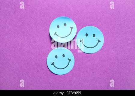 Sticky notes with smiley faces on purple background Stock Photo