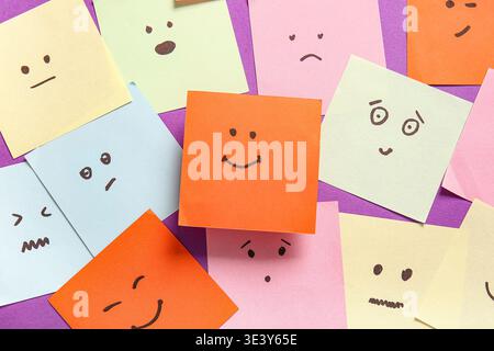Sticky notes with drawings of different emotion faces on purple background Stock Photo