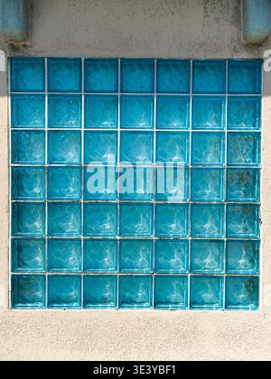 Abstract background of a glass block wall with square cells. Close-up view of industrial translucent material with a grid pattern and diffused light. Stock Photo