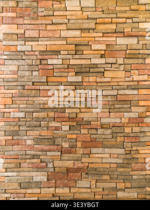 Horizontal surface of a stone wall made of various rectangular blocks with different shades of brown. Modern architectural cladding with natural stone. Stock Photo