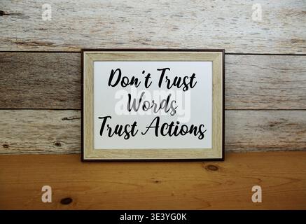 Don't Trust Words  Trust Actions text written in horizontal frame standing on wooden surface Stock Photo