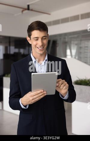 Professional man smiling and using digital tablet in office Stock Photo