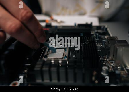 Technician applying thermal paste on computer processor, spreading precise layer for efficient cooling and improved performance during hardware Stock Photo