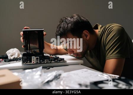Concentrated computer technician carefully installing CPU cooler onto motherboard, performing maintenance and upgrade service on desktop computer Stock Photo