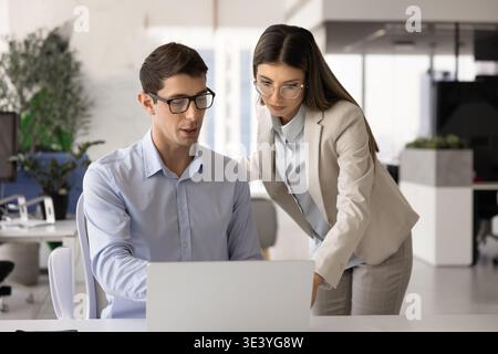 Colleagues working on task using laptop in contemporary workplace Stock Photo