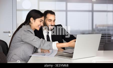 Multiethnic business colleagues reviewing data on laptop in office Stock Photo