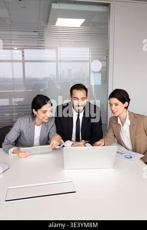 Business team, executive managers gather around laptop in office boardroom Stock Photo
