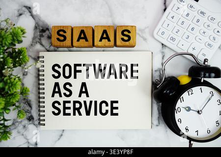 SAAS Software As A Service Is A Software text with calculator and alarm clock on marble background Stock Photo