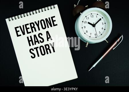 Everyone Has A Story text written on notepad with pen and alarm clock Stock Photo
