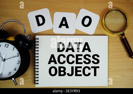 DAO Data Access Object text written on notepad with magnifying glass and alarm clock on wooden background Stock Photo