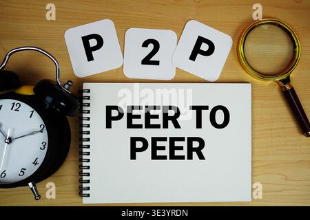 P2P Peer to Peer text written on notepad with magnifying glass and alarm clock on wooden background Stock Photo