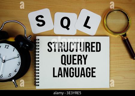 SQL Structured Query Language text written on notepad with magnifying glass and alarm clock on wooden background Stock Photo