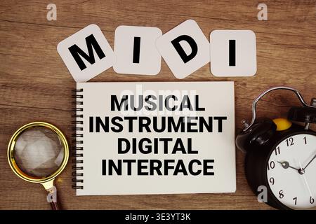 MIDI Musical Instrument Digital Interface text written on notepad with magnifying glass and alarm clock on wooden background Stock Photo