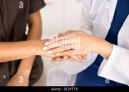 Closeup of female doctor holding and stroking female patient hands Stock Photo