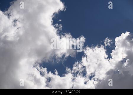 Calm blue sky with fluffy white clouds drifting gently. Peaceful and serene, perfect for relaxation or travel themes. Ideal for backgrounds in wellnes Stock Photo