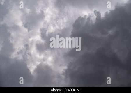 Storm clouds gather thickly overhead, casting ominous gray shadows. Light breaks through cloud gaps, highlighting dramatic textures. Atmosphere feels Stock Photo