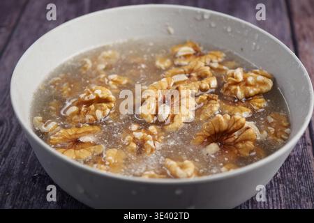 Walnuts soaking in water on a wooden table Stock Photo