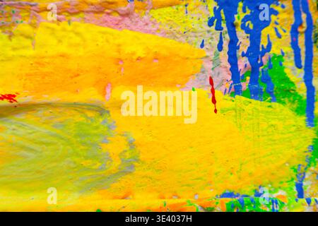 Energetic abstract canvas featuring multicolored acrylic splatters and streaks in green, yellow, blue, orange, pink, and purple for creative backgroun Stock Photo
