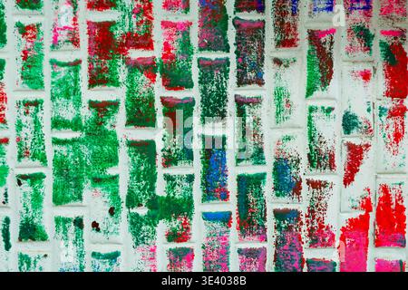 Close-up of a brick-tiled studio wall textured with years of accumulated green, red paint splatters, reflecting the organic of a creative workspace. Stock Photo