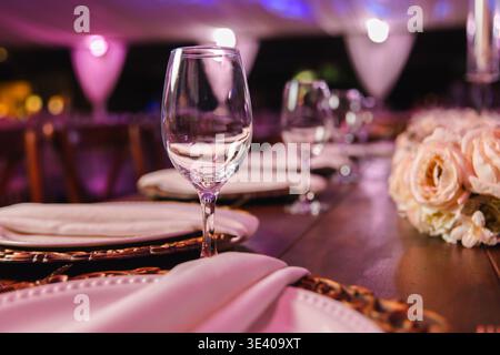 Elegant table setting in soft pink tones with refined dinnerware and folded napkins. Stock Photo
