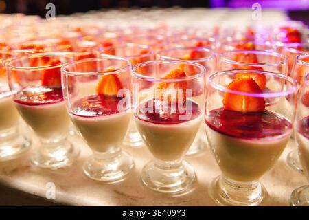 Panna cotta dessert cups topped with fruit and sauce. Stock Photo