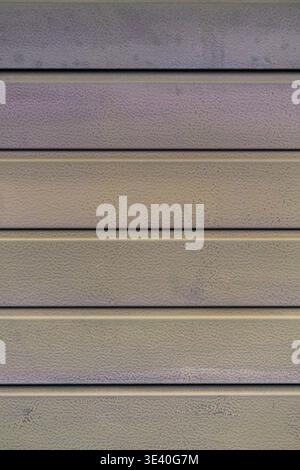 Close up of metal wall with horizontal panels and fine textured surface. Industrial abstract background with linear pattern and muted tones. Stock Photo