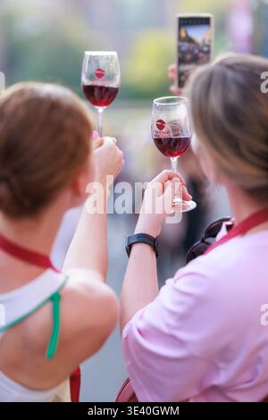 At Yerevan Wine Days Festival  two visitors holding glasses of red wine while taking a photo during the festival in Yerevan, Armenia. Stock Photo