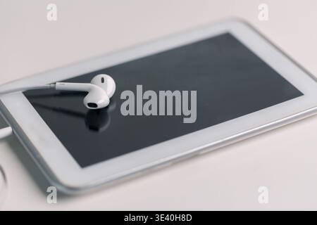 New technology modern Close up high resolution Wireless Earphones white Earbuds headphones black blur background Trendy minimal music device laptop co Stock Photo
