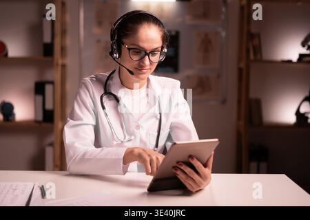 Female doctor wearing headset with digital tablet at the clinic during night shift. copy space Stock Photo