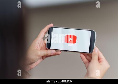 CHIANG MAI ,THAILAND - MAR 18, 2026 : A women using Youtube application on her iPhone Stock Photo
