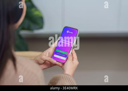 CHIANG MAI ,THAILAND MAR 18 2026 : Woman hand holding iPhone 17 with Spotify login screen. Spotify is a music service that offers legal streaming Stock Photo