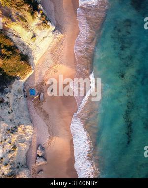Aerial view of golden sands meeting turquoise waters, where cliffs cast long shadows on a secluded beach, Vejer de la Frontera, Andalusia, Spain. Stock Photo