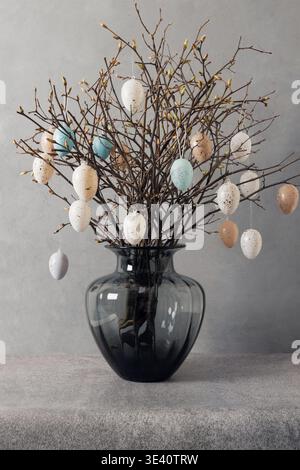 Easter tree decorated colorful pastel white and beige eggs. Birch branches with hang eggs in vase on gray background. Vertical format. Happy Easter greeting card. Stock Photo