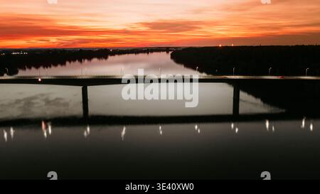 Aerial view of the bridge over the Sava River reflects the fiery sunset, casting a warm glow over the landscape, Sremska Mitrovica, Vojvodina, Serbia. Stock Photo