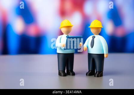 Two engineers with plans and wearing yellow hard hats. Development and design, construction, and engineering. Industrial teamwork builds infrastructur Stock Photo