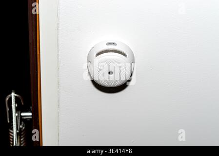 Wireless smoke detector mounted on a white wall providing fire safety and security Stock Photo