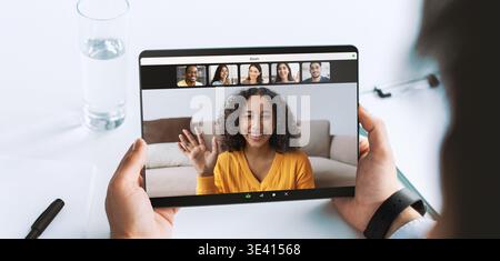 Millennial Doctor Conducts Online Consultation Using Tablet on Desk During Video Conference Stock Photo