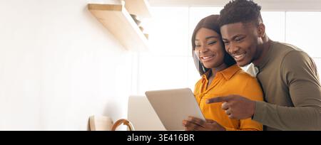 Happy Black Couple Using Digital Tablet While Cooking Food Together In Kitchen Stock Photo