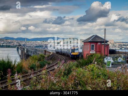 Passenger train rounds a curved section of track across the Tay Estuary near Wormit, Fife, Scotland, passing a red signal box on the historic rail bri Stock Photo