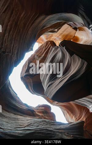 Layered sandstone slot canyon with smooth eroded rock formations and narrow passage opening in a desert landscape Stock Photo