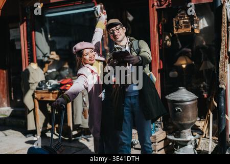 Diverse tourists taking a joyful selfie outside a vintage street market during city travel Stock Photo