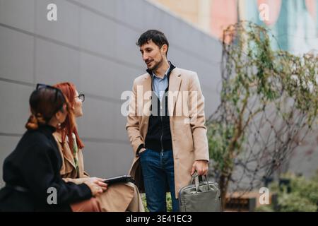 Business workers having a casual outdoor conversation near office building in urban setting Stock Photo