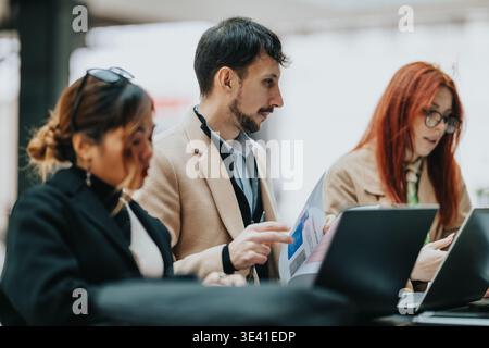 Business workers collaborating over laptops and documents in a modern coworking space Stock Photo