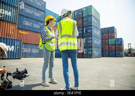 Two construction workers using tablet and clipboard at shipping container site Stock Photo