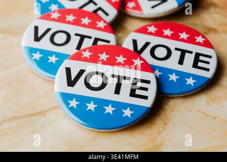 close view of several red, white, and blue vote badges grouped on a marble background, political election symbol encouraging citizens to participate a Stock Photo
