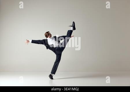 Businessman stretching leg in wide dynamic pose wearing formal suit on clean background Stock Photo