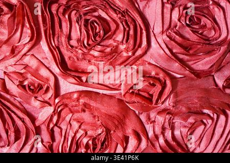 Close-up of satin fabric folded into rose-like floral patterns with rich sheen and layered texture. Stock Photo