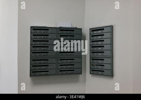 Set of metal mailboxes mounted on white wall inside residential building hallway. Concept of communication, delivery, apartment living and everyday Stock Photo
