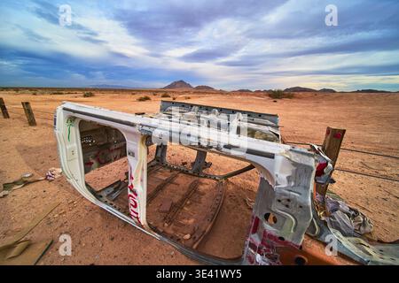 Abandoned Vehicle Shell in Nevada Desert with Mountains and Dramatic Sky Stock Photo