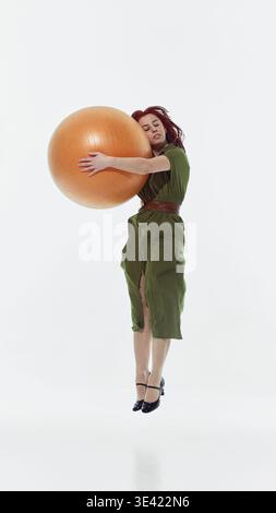 Woman holding large exercise ball standing in studio isolated on white Stock Photo